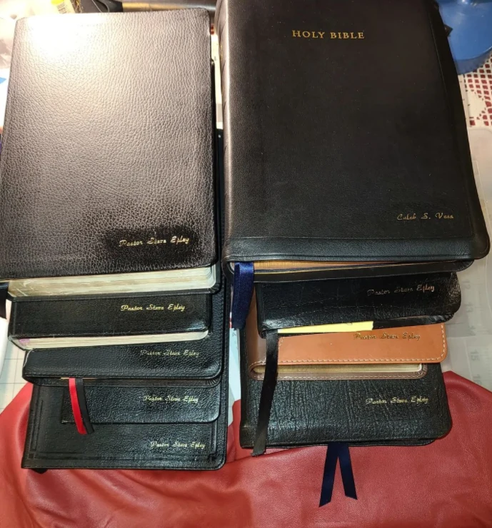 Stacked custom Bibles with leather covers, gold imprinting, and colorful ribbon markers.