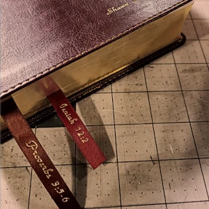 Close-up of a leather Bible with gilt page edges and red scripture ribbons.